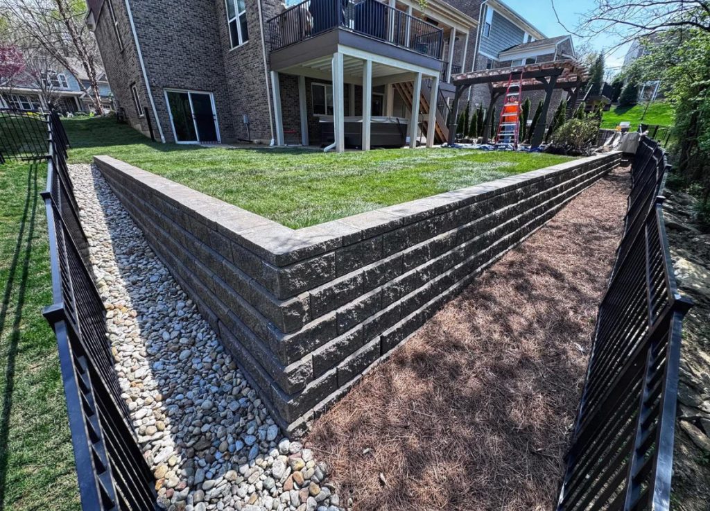 Tiered retaining wall with fresh sod and decorative edging.